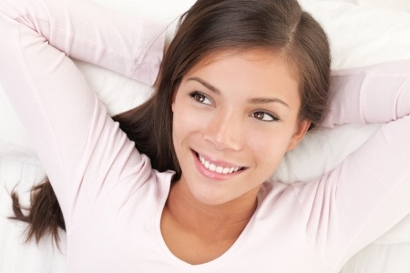 6813854 - woman smiling daydreaming and relaxing in bed. beautiful multiracial chinese / caucasian young woman model.